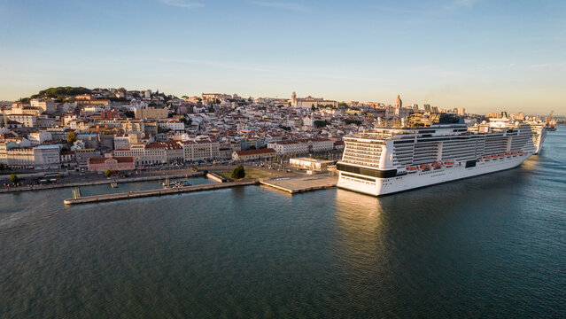 aerial drone view of a large cruise ships moored at Lisbon port, Portugal with Lisbon landmarks in the background