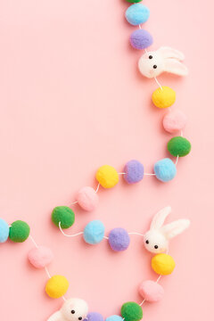 Flat lay image of colorful felt Easter rabbit garland on pink surface