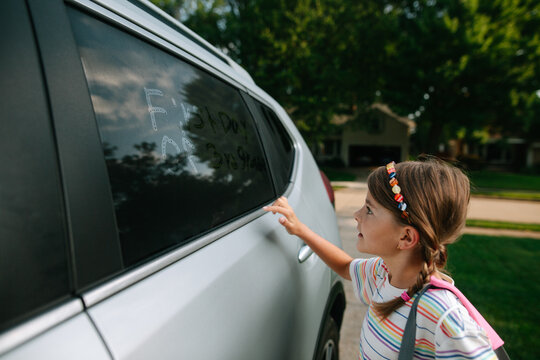 child writes on car window
