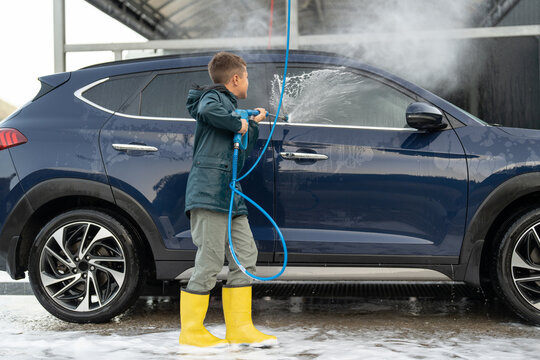 Kid is washing vehicle at manual car wash station