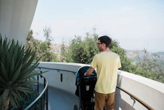 Young Dad Pushing A Stroller Along Path