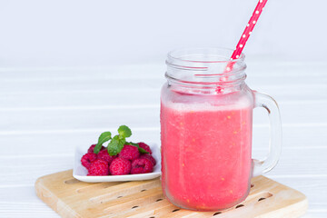 Raspberry smoothie red colorful fruit juice milkshake blend beverage healthy high protein the taste yummy In glass drink episode morning on white wood background.