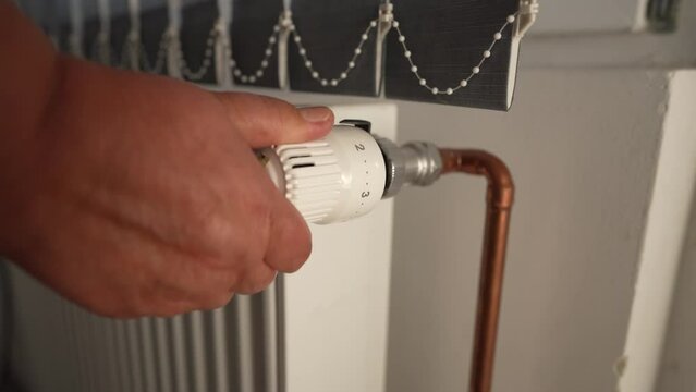 Close up on hand of unknown woman turning off heat on the radiator in the apartment energy and gas crisis concept