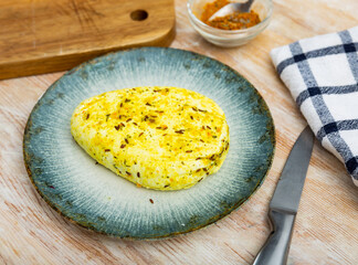 Plate with slab of fried flavorful cottage cheese seasoned with cumin seeds and turmeric standing...