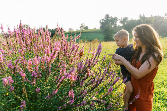 Mother holding her son and showing him a monarch butterfly