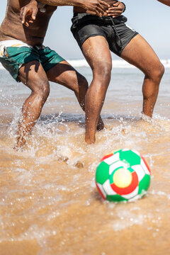 anonymous black men playing with ball on the beach