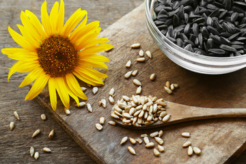 Obraz na płótnie Canvas Sunflower seeds and flower on wooden table