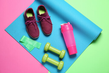 Exercise mat, dumbbells, fitness elastic band, shoes and shaker on color background, top view