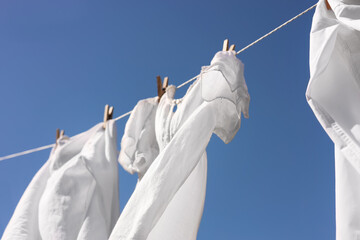 Clean clothes hanging on washing line against sky, low angle view. Drying laundry
