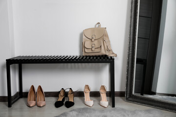 Fototapeta na wymiar Stylish shoes near bench with backpack in hallway. Interior design