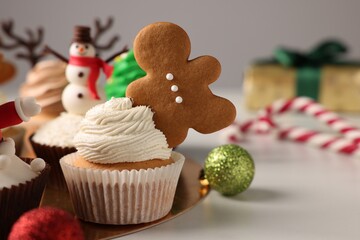 Tasty Christmas cupcake with gingerbread man and baubles on white table. Space for text