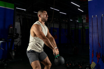 latin man exercising with a kettlebell in a gym