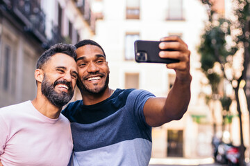 Multiracial couple taking a selfie with smartphone outdoors
