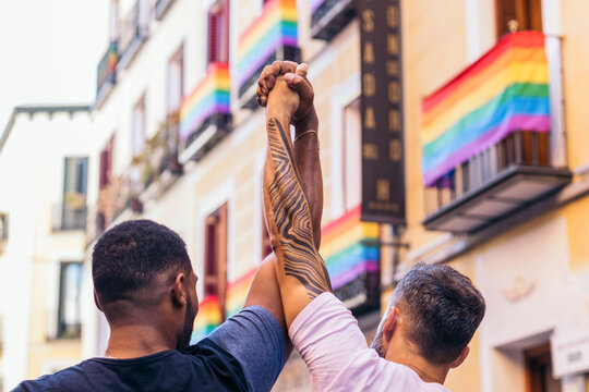 Interracial gay couple raising their hands claiming their love