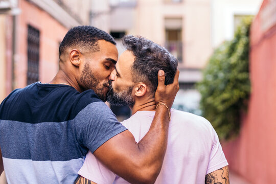Multiracial gay couple walking and kissing on the street