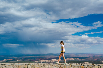 Girl balances on the wall of an overlook