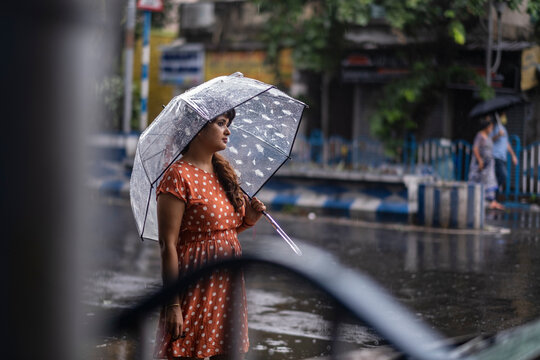 Indian woman withstanding beside roan in a rainy day at outdoors 