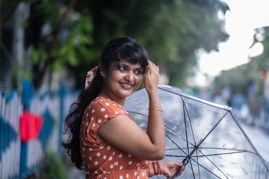 Indian woman withstanding beside roan in a rainy day at outdoors 