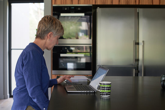 Woman sitting at kitchen bench working on computer