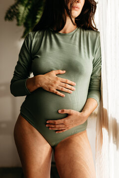 a pregnant woman wears a green bodysuit