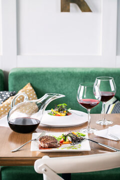 Steak and  Red wine served in a decanter and wine glasses