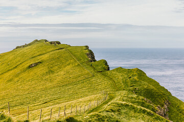 Green landscape under cloudy sky in Faroe Islands