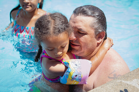 Father holding his young child as they sit in a pool