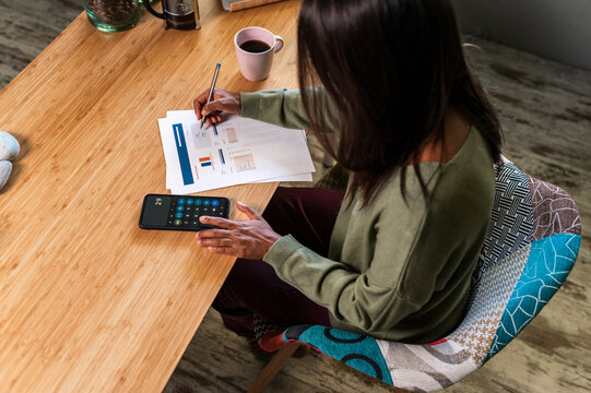 Hispanic woman calculating expenses at home