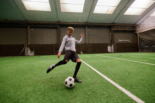 Teenager practicing to on football pitch