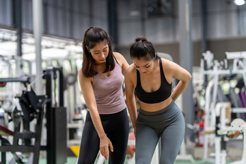 Fototapeta premium Female fitness instructor showing exercise progress to a young athletic woman at the gym and smiling cheerfully while exercising with his fitness coach and training.