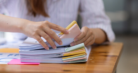 Close up of Business hands working in Stacks of paper files for searching information on work desk workplace office, Office employee working with documents achieves with clips at table in workplace.