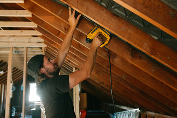 man uses nail gun in construction home