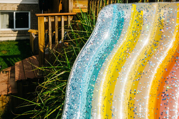 Glittery rainbow pool float next to the deck