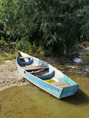 Fototapeta premium An old blue boat stands on the shore of the lake.