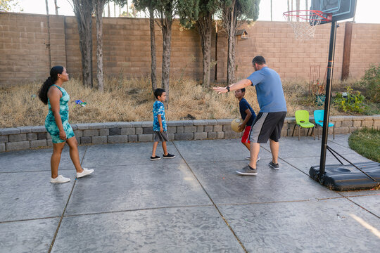 United family with children playing basketball outdoors