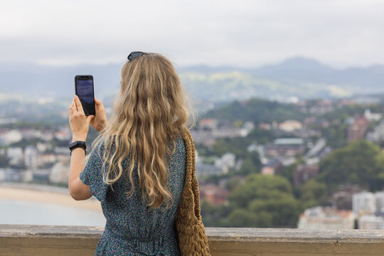 Young woman photographing city of San Sebastian, Spain.