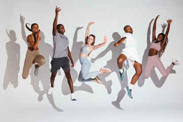 Multiracial sportspeople jumping with raised arms
