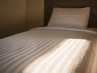 Hotel Bedroom Bed duvet and pillow with morning sunlight 