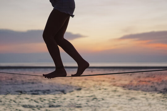Close up of female feet walking on the slackline during a sunset