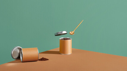 Instant coffee in a paper-tin can with spoon on a brown surface