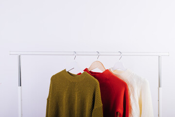 Three colorful sweaters on hangers