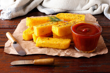 Fried polenta sticks in paper over rustic wooden table