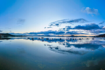 Aerial sunrise waterscape with boats, rain clouds and reflections