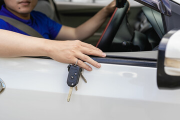A handsome young man in a blue t-shirt in a hat holding his new car keys and smiling. Asian man with car keys in hand . The idea of ​​having a new car.