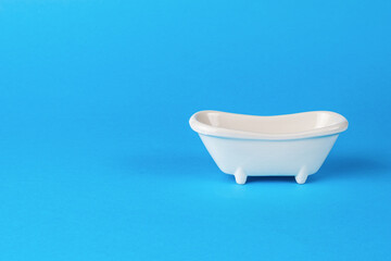 Classic white bathing tub on a blue background. Minimal concept.