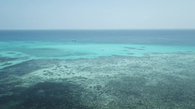 Drone aerial pan around over the Great Barrier Reef with boats on the tropical clear blue water