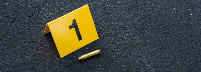 One yellow crime scene evidence marker on the street after a gun shooting brass bullet shell casing rifle - obrazy, fototapety, plakaty