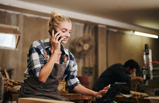 Artisan woman talking the phone in carpentry workshop.