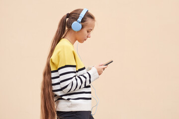 Profile view of serious teenager girl listening to music with blue headphones