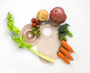Two piece ostomy appliance including flange, pouch with vegetables isolated a white background.
